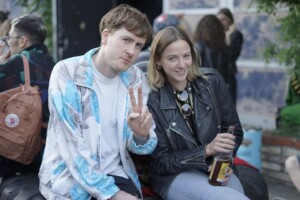 outdoor guests at bmva guy with blue and grey shirt and girl with skin jaket are drinking matte and looking to the camera at the festival